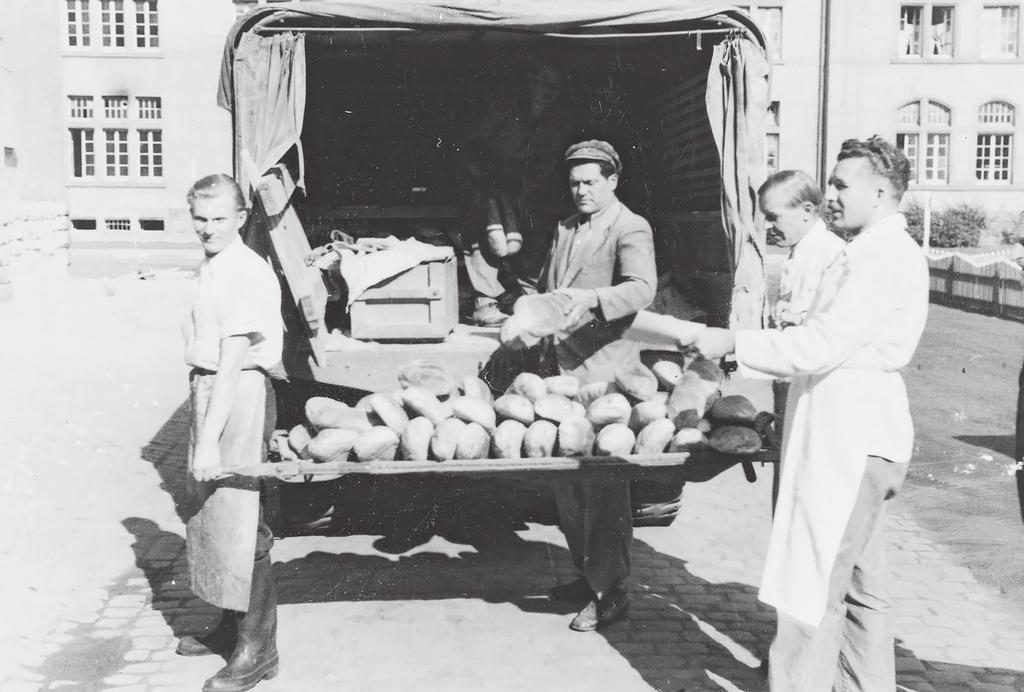 Foto 2. Leivajagamine Wiesbadeni põgenikelaagris 1946. aastal. Oskar Kuusik (valge põllega) vastu võtmas laagri päevast leivanormi.